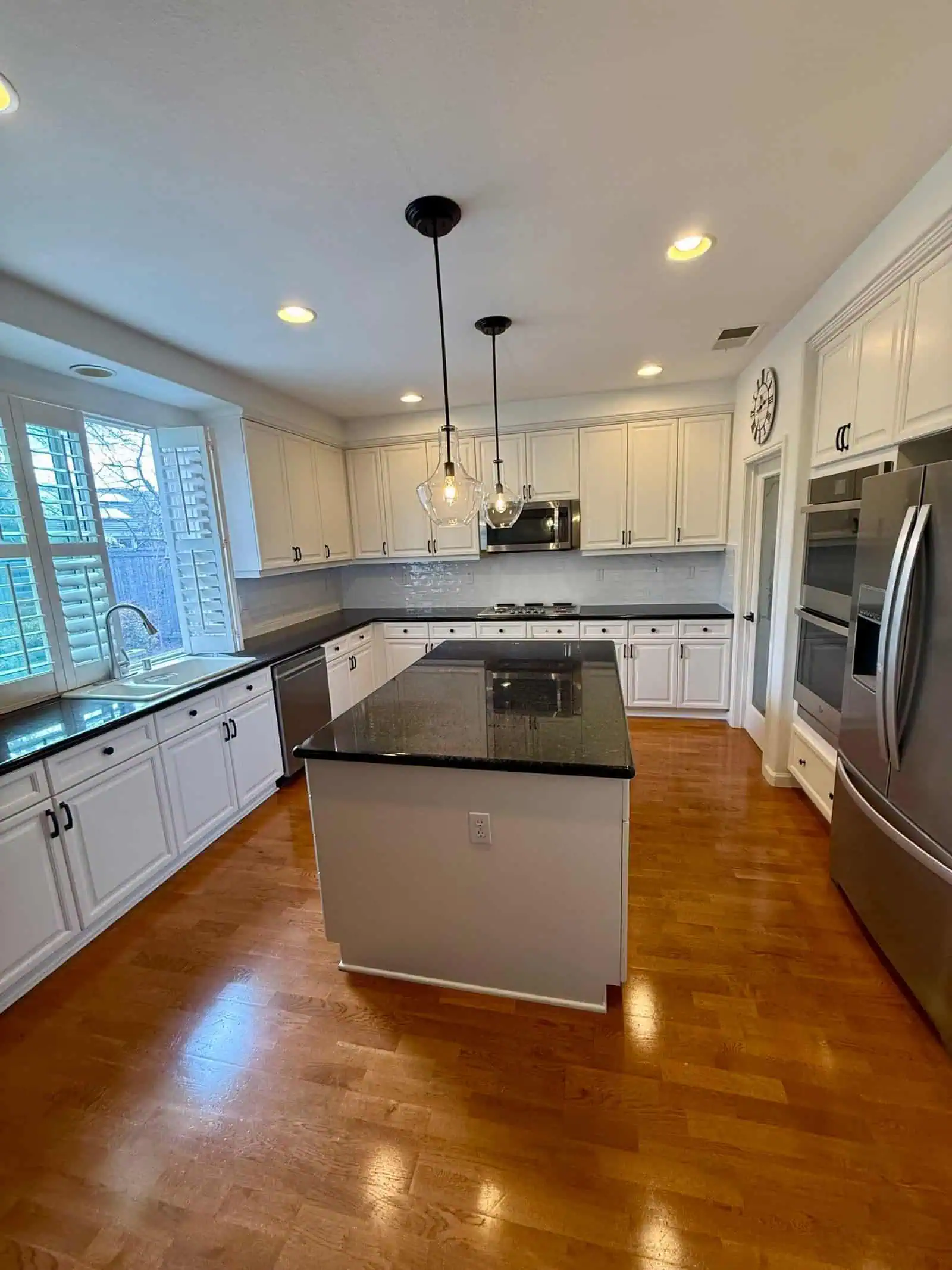 Bright and spacious kitchen featuring white cabinetry, a central island with a black countertop, and.