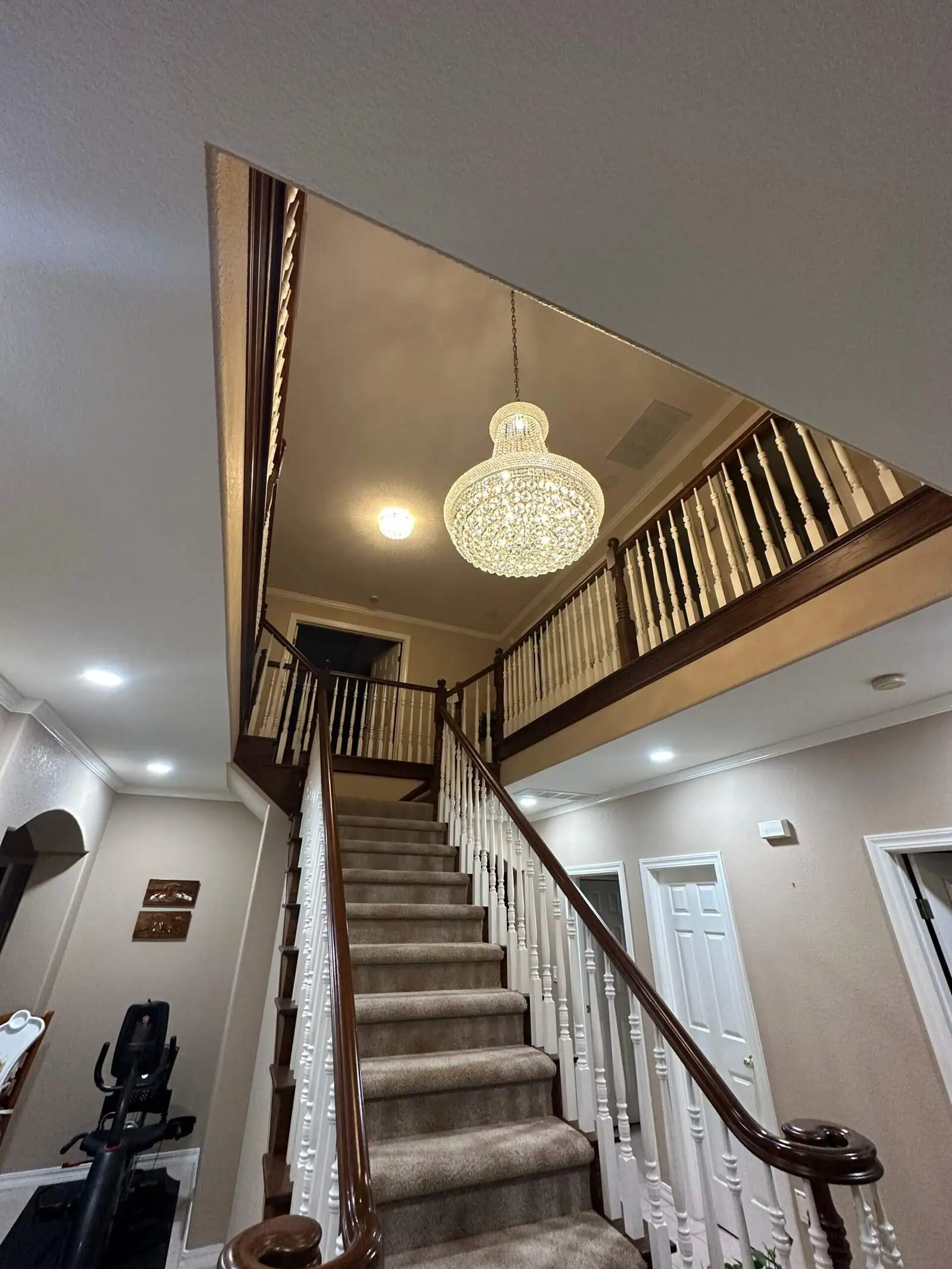 Elegant staircase with a chandelier in a modern home interior.