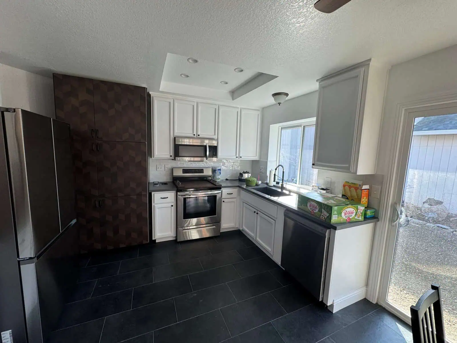 Kitchen with stainless steel appliances, white cabinets, and natural light.