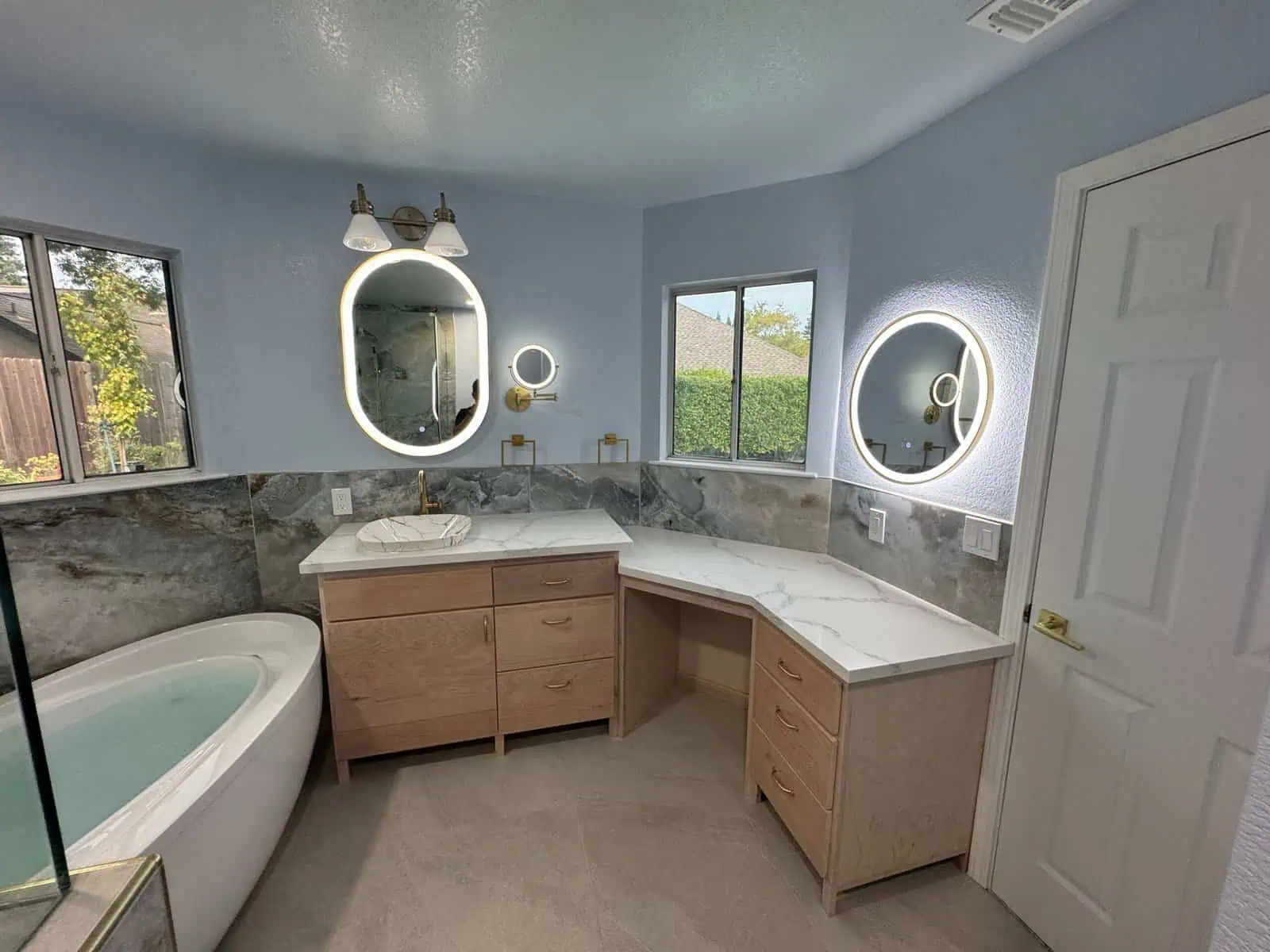 Bathroom with double vanity, illuminated mirrors, and soaking tub for relaxation.