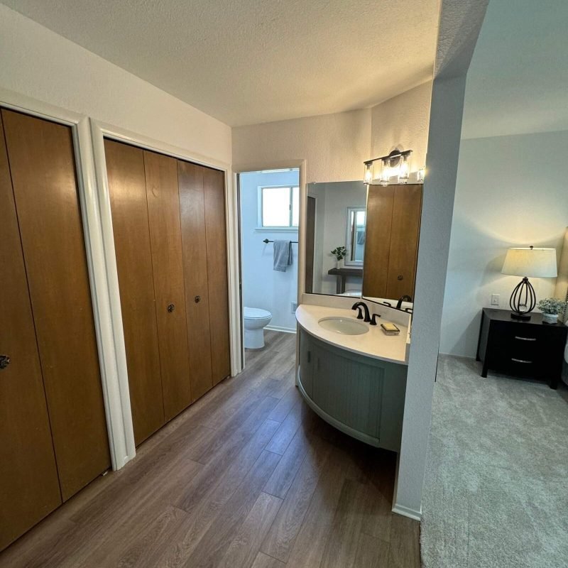 Bathroom with wooden closet doors, sink, and mirror.