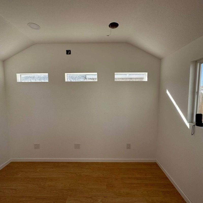 Bright interior room with large windows and white walls for natural light.